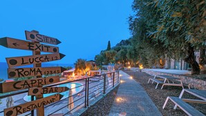 A wooden signpost with directions to various local attractions such as 'Exit', 'Lucca', 'Roma', 'Capri', and 'Bar'.