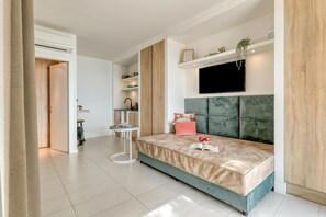 A modern bedroom with a bed, a TV, and a small table.