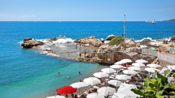 A beach with rocky terrain, clear blue water, and a row of umbrellas. - Boutique Pool Apt. Balzi Rossi - Roma 4, Ventimiglia, Italy (Ventimiglia)