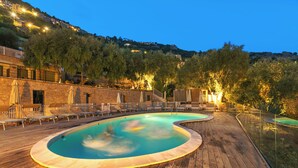 A wooden deck with a swimming pool, lounge chairs, and a view of a hillside with buildings. - Boutique Pool Apt. Balzi Rossi - Roma 4, Ventimiglia, Italy (Ventimiglia)