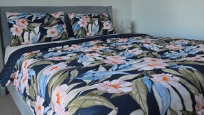 Ein Schlafzimmer mit einem Bett, floralem Bettbezug, einem Fenster und einer Klimaanlage.