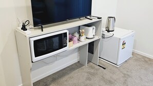 Eine kleine Küchenzeile mit Mikrowelle, Wasserkocher und kleinem Kühlschrank.