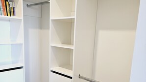Ein begehbarer Kleiderschrank mit offenen Regalen und einer Kleiderstange.
