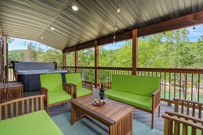 Un patio techado al aire libre con una parrilla, asientos y vistas del bosque circundante.