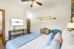 Un dormitorio con cama, escritorio, silla y ventilador de techo.