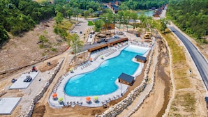 A resort with a large swimming pool, lounge areas, and a view of the surrounding forested hills.