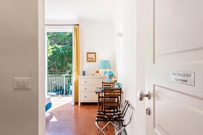 Una habitación con balcón, una mesa con sillas, una lámpara y un cartel que indica 'MINI BALCONY Apartment'.