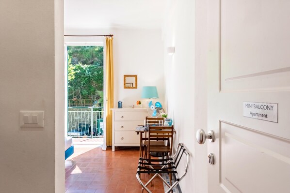 Une chambre avec un balcon, une table avec des chaises, une lampe et un panneau indiquant « Appartement avec PETIT BALCON ».
