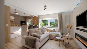 A modern living room with a sofa, a fireplace, a TV, and a view of the outdoors. - Holiday Apartment 'My Little Suite' with Wi-Fi (Illingen)