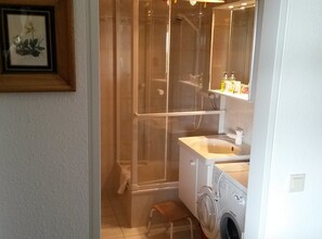 Une salle de bain avec une douche, un lavabo et un lave-linge.
