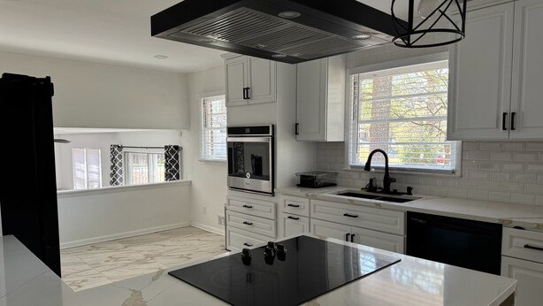 A modern kitchen with white cabinetry, a black induction cooktop, a stainless steel oven, and a window with blinds. - Charming 3-bedroom house in Atlanta with AC, WiFi (Atlanta)