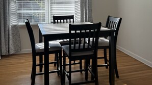 A dining area with a table and four chairs, a window with blinds, and curtains. - Charming 3-bedroom house in Atlanta with AC, WiFi (Atlanta)