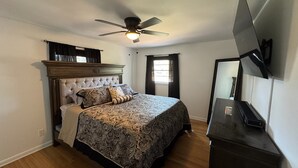 A bedroom with a bed, a ceiling fan, a TV, and a window. - Charming 3-bedroom house in Atlanta with AC, WiFi (Atlanta)