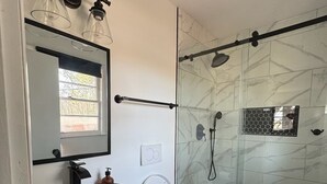 A modern bathroom with a black vanity, a round sink, a white toilet, and a glass shower enclosure. - Charming 3-bedroom house in Atlanta with AC, WiFi (Atlanta)