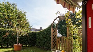 A patio with a table, a potted plant, and a wooden gate.