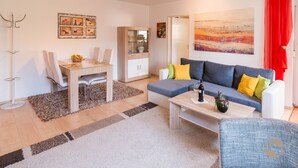 A modern living room with a sofa, coffee table, and dining area.