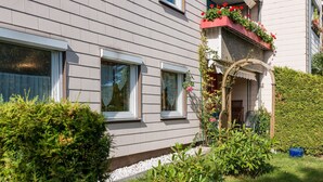 A residential house with a front garden, a wooden fence, and a small porch with a flower box.