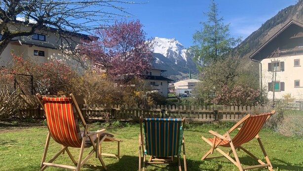 A grassy area with three wooden chairs and a wooden fence. - Holiday Home 'Durst 1' with Mountain Views, Private Terrace and Wi-Fi (Mayrhofen)