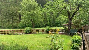 A lush green garden with a wooden fence, a bench, and a variety of trees. - Holiday Home 'Durst 1' with Mountain Views, Private Terrace and Wi-Fi (Mayrhofen)
