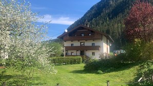 A two-story chalet with a balcony, surrounded by a well-maintained lawn and a mountain backdrop. - Holiday Home 'Durst 1' with Mountain Views, Private Terrace and Wi-Fi (Mayrhofen)