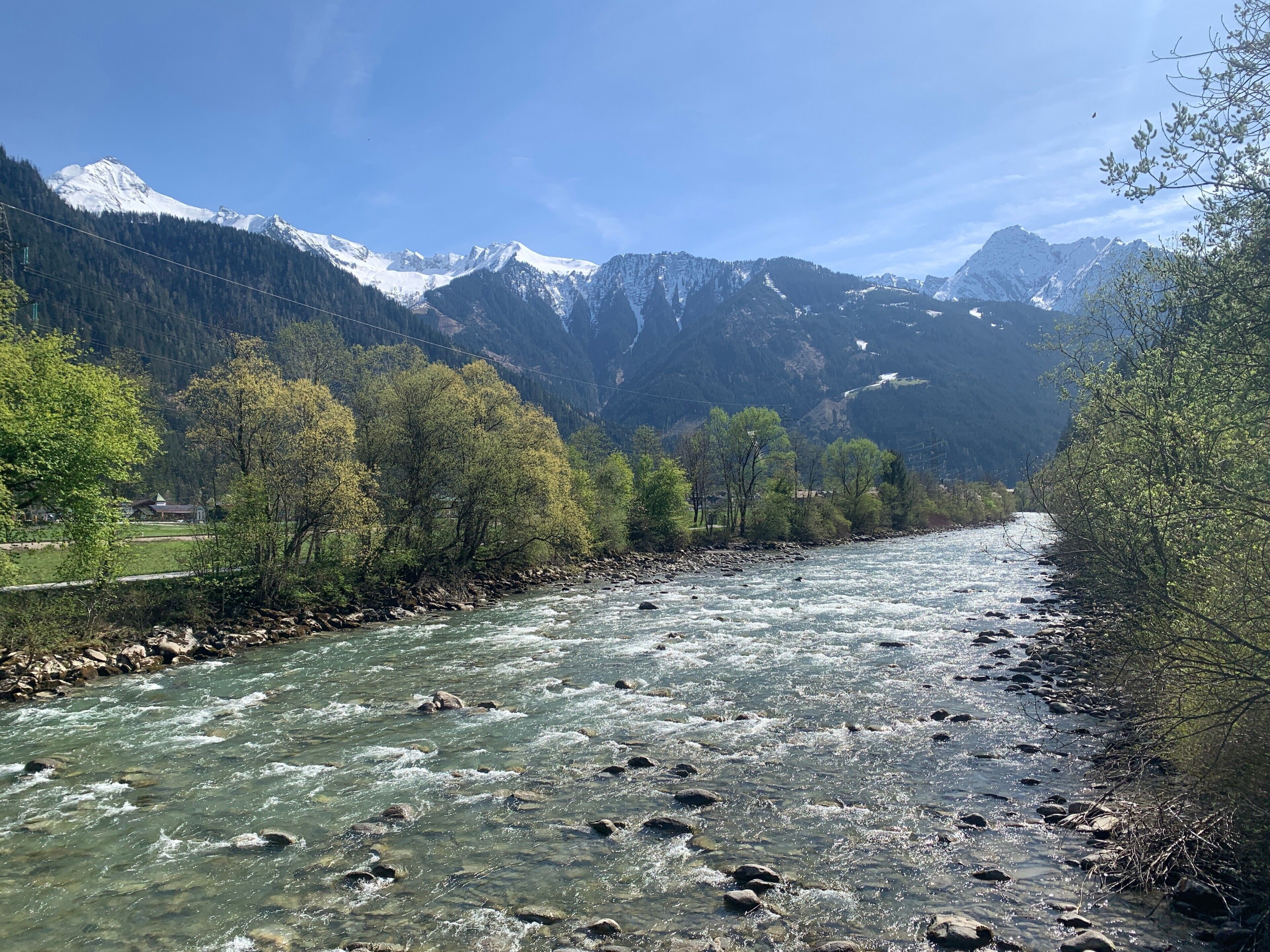 Une rivière qui traverse une vallée, avec des montagnes en arrière-plan.