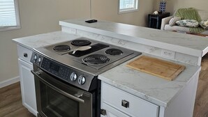 Une cuisine moderne dotée d’une cuisinière et d’un four intégrés, ainsi que d’un plan de travail en marbre.