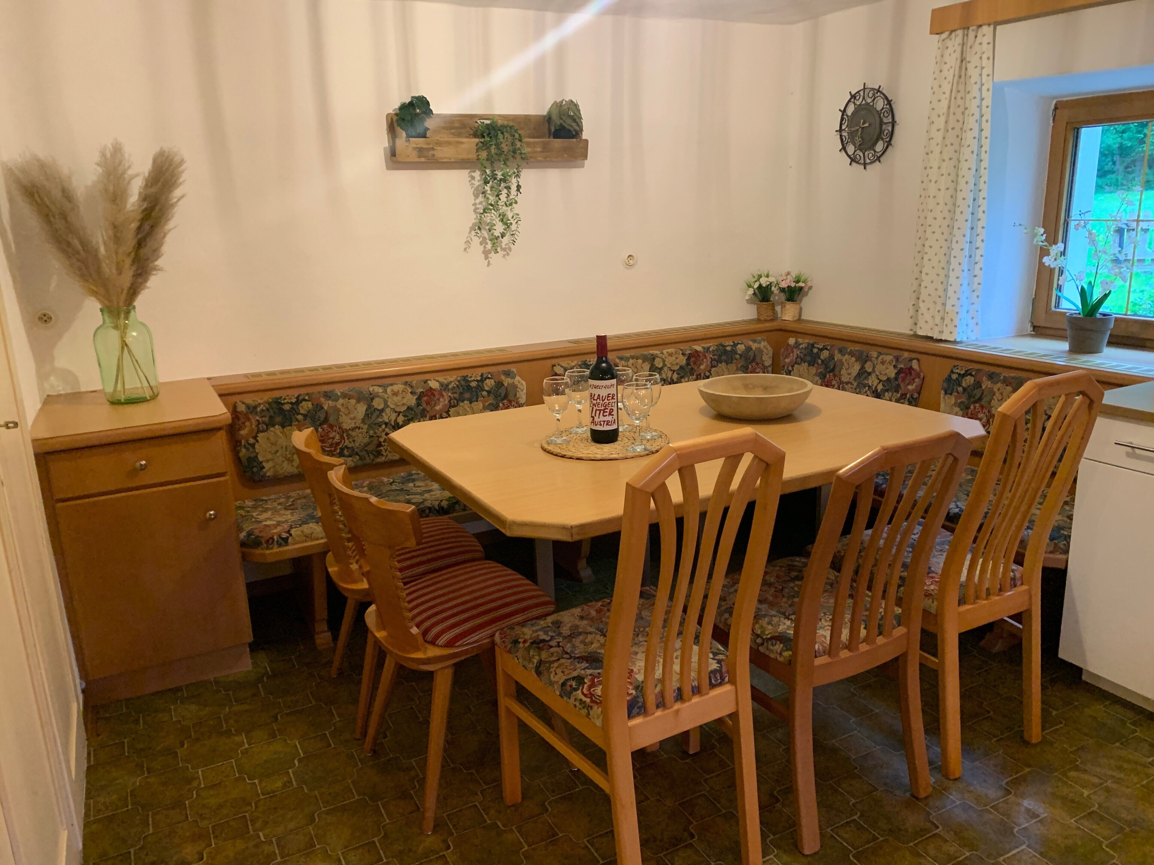 Ein Essbereich mit einem Holztisch, Stühlen, einer Bank und einem kleinen Regal mit Pflanzen.