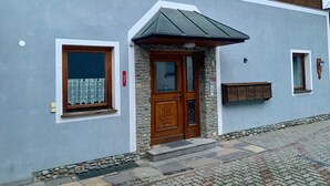 A building with a stone facade, a wooden door, and a small window with a curtain.