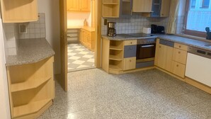 A kitchen with wooden cabinets, a stainless steel oven, and a checkered floor.