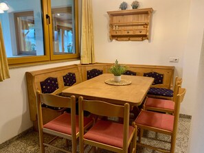 A corner dining area with a wooden table and chairs, a potted plant, and a wooden cabinet above. - Apartment 'Auner Top 1' with Mountain View, Private Terrace and Wi-Fi (Westendorf)