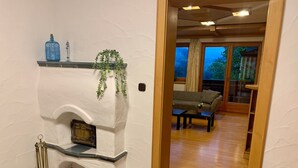A room with a fireplace, a sofa, and a view through a doorway.