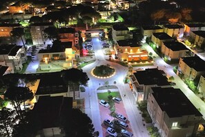 Un quartier résidentiel comprenant plusieurs immeubles, un rond-point et des voitures garées.