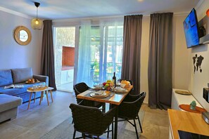 Un salon moderne comprenant un canapé, une table à manger, des chaises et un téléviseur.