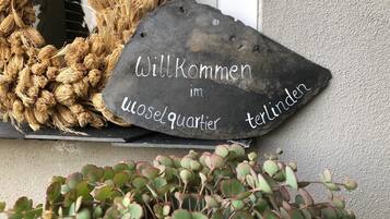 A welcome sign with text, a woven wreath, and a potted plant.