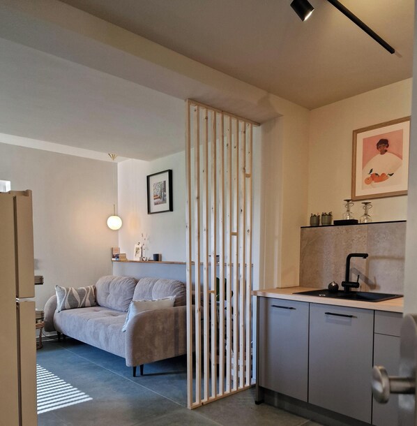 Un apartamento moderno con kitchenette, un sofá, una mesa de comedor y un ventanal grande.