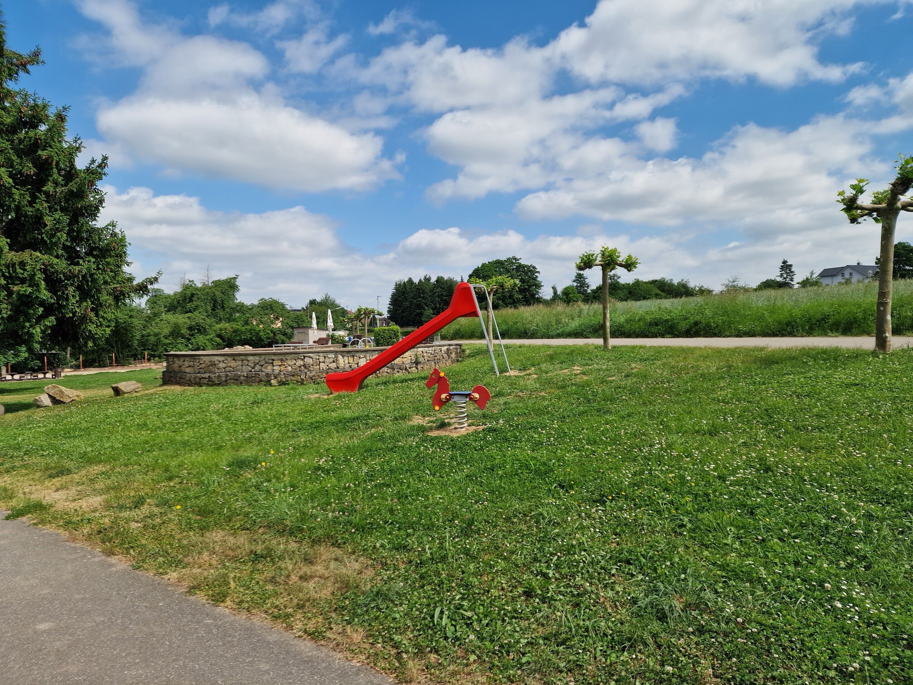 A playground with a red slide and a merry-go-round.