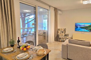A modern living room with a dining area, a sofa, a television, and a view of a mountain landscape. - SanPietro Holiday Homes 285, Lalzit Bay, Albania (Lalzit Bay)