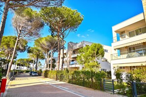 A residential street with modern buildings, a paved road, and trees. - SanPietro Holiday Homes 285, Lalzit Bay, Albania (Lalzit Bay)