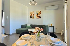 A modern dining area with a round table set for four, a vase with flowers, and abstract art on the wall.