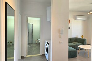 A modern living room with a green sofa, a white table, and a washing machine.