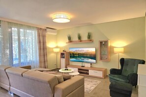 A modern living room with a sofa, a television, and a green armchair.