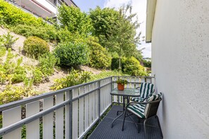 A balcony with a metal railing, a small table with a potted plant, and two wicker chairs. - Apartment 'Hacke, 55qm' with Balcony and Wi-Fi (Schmallenberg)