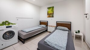 Una camera da letto con due letti, una lavatrice, un piccolo armadietto e una mensola a parete.