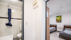 Una stanza con bagno privato, un letto, una piccola credenza e un quadro appeso al muro.