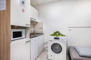 A compact kitchen with a microwave, sink, and a washing machine.