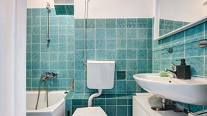 A bathroom with a bathtub, toilet, sink, and a mirror.