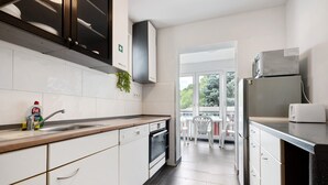 A modern kitchen with white cabinetry, a built-in oven, a stainless steel refrigerator, and a window providing a view of the outdoors.