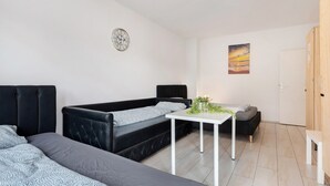 Quarto moderno com sofá preto, mesa branca e um quadro na parede.