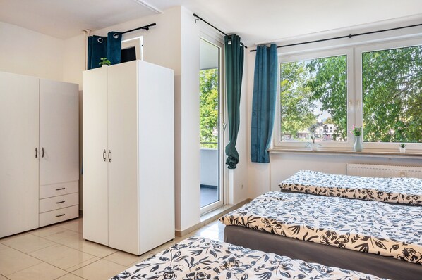 Un dormitorio con cama, armario, ventana con cortinas y vistas a árboles.