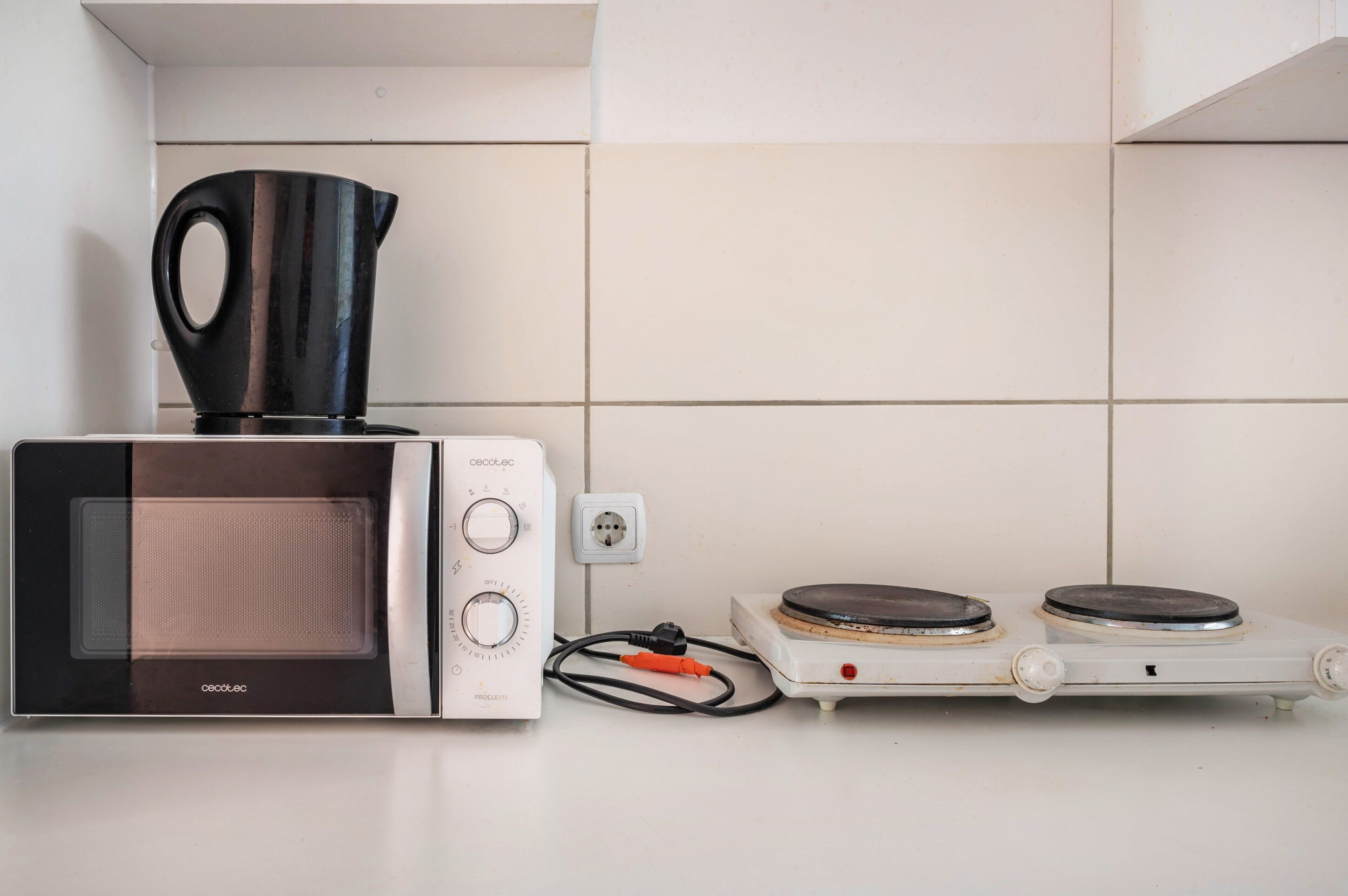 Een kitchenette met een magnetron, waterkoker en elektrische kookplaat.